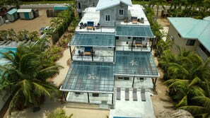 A multi-story building with a flat roof, multiple balconies, and a pool area. - Conmigos 3 Bedroom Condo - Unit 2 (Placencia)