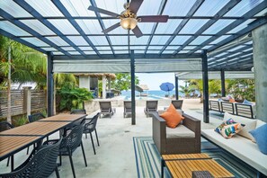 An outdoor patio with a pool, lounge chairs, and a covered seating area with a view of the ocean. - Conmigos 3 Bedroom Condo - Unit 2 (Placencia)