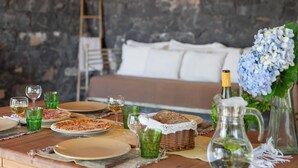 Uma mesa de madeira posta com pratos, copos, uma cesta de pão e um jarro.