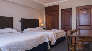 A hotel room with two beds, a wooden table, and a ceiling fan. - Econohotel (Los Angeles)