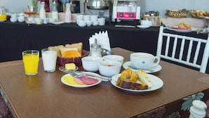 A breakfast table with various food items and beverages, a coffee machine, and a buffet in the background. - Econohotel (Los Angeles)