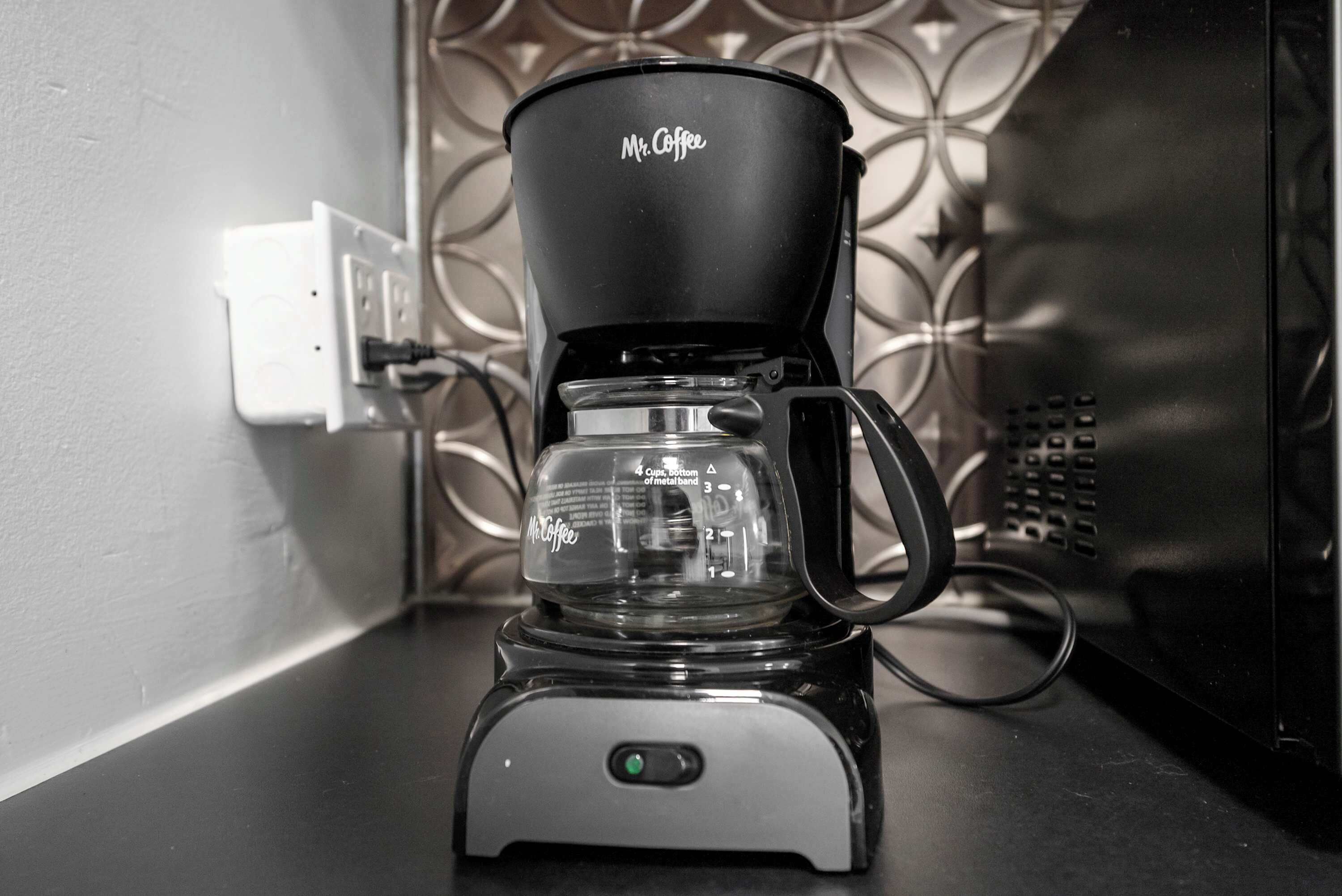 A Mr. Coffee coffee maker on a countertop with a patterned backsplash.