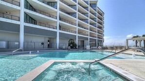 Un hôtel à plusieurs étages doté d’une piscine, d’un espace extérieur aménagé et d’un palmier.