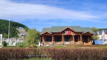 A wooden building with a green roof, a porch, and a flag.