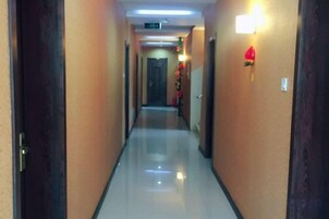 Pasillo de hotel con puertas a ambos lados, un adorno iluminado en la pared y un suelo reflectante.