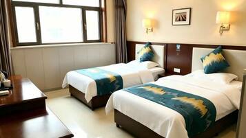 A hotel room with two beds, a desk, and a window with curtains.