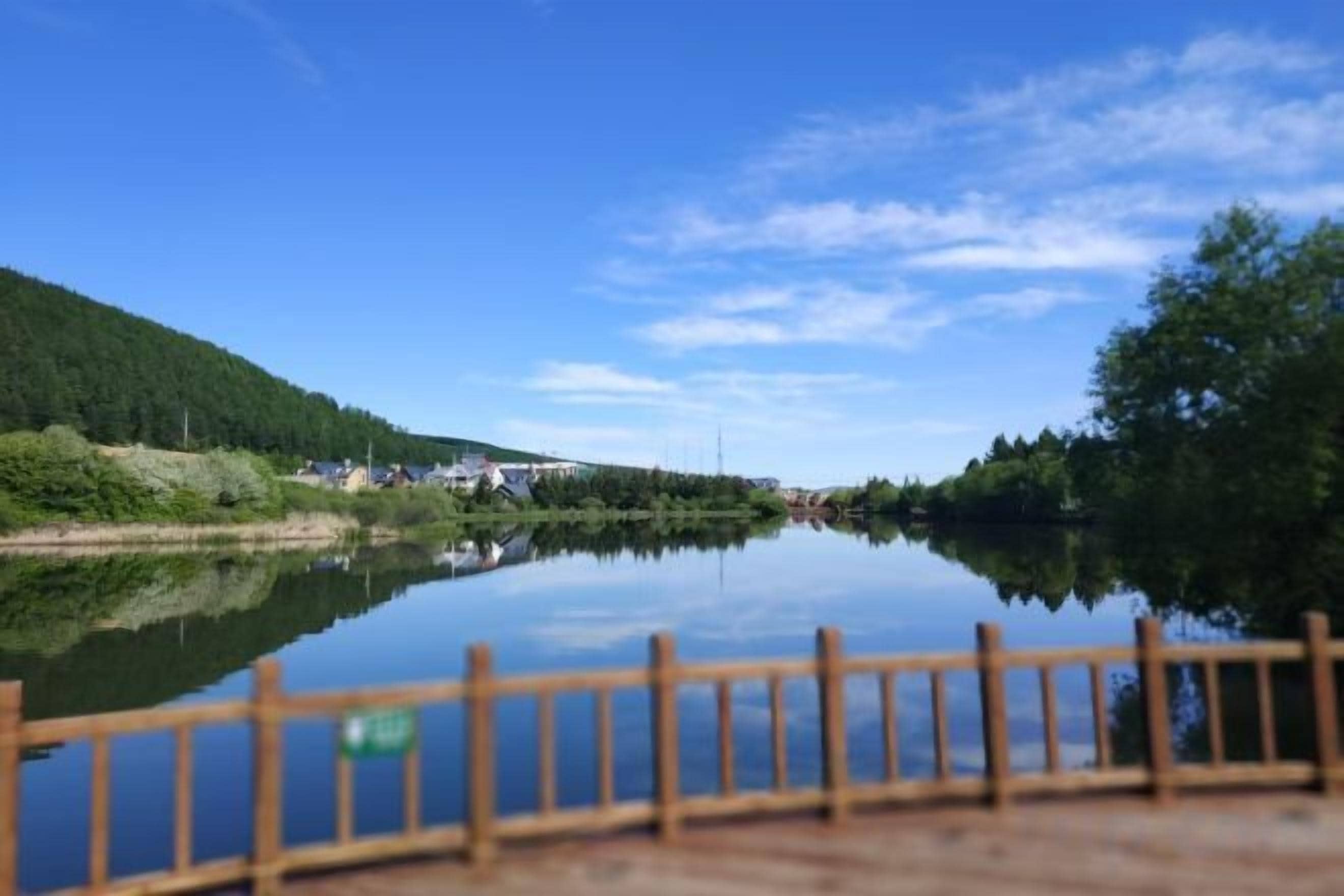 Ein ruhiger Fluss mit einer Holzsteganlage und blauem Himmel.