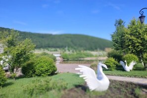 A park with swan statues and a clear view of a distant hill. - Xinchangcheng Hotel (Arxan)