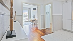 Ett modernt hotellrum med trägolv, en matplats med bord och stolar samt utsikt över staden genom stora fönster.