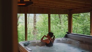Una cabaña de madera con jacuzzi y vista al bosque.
