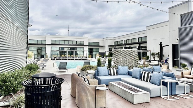 An outdoor patio with seating, a pool, and a modern building in the background. - Ceiling to floor windows featuring a private balcony with stunning city views! 
 (Atlanta)