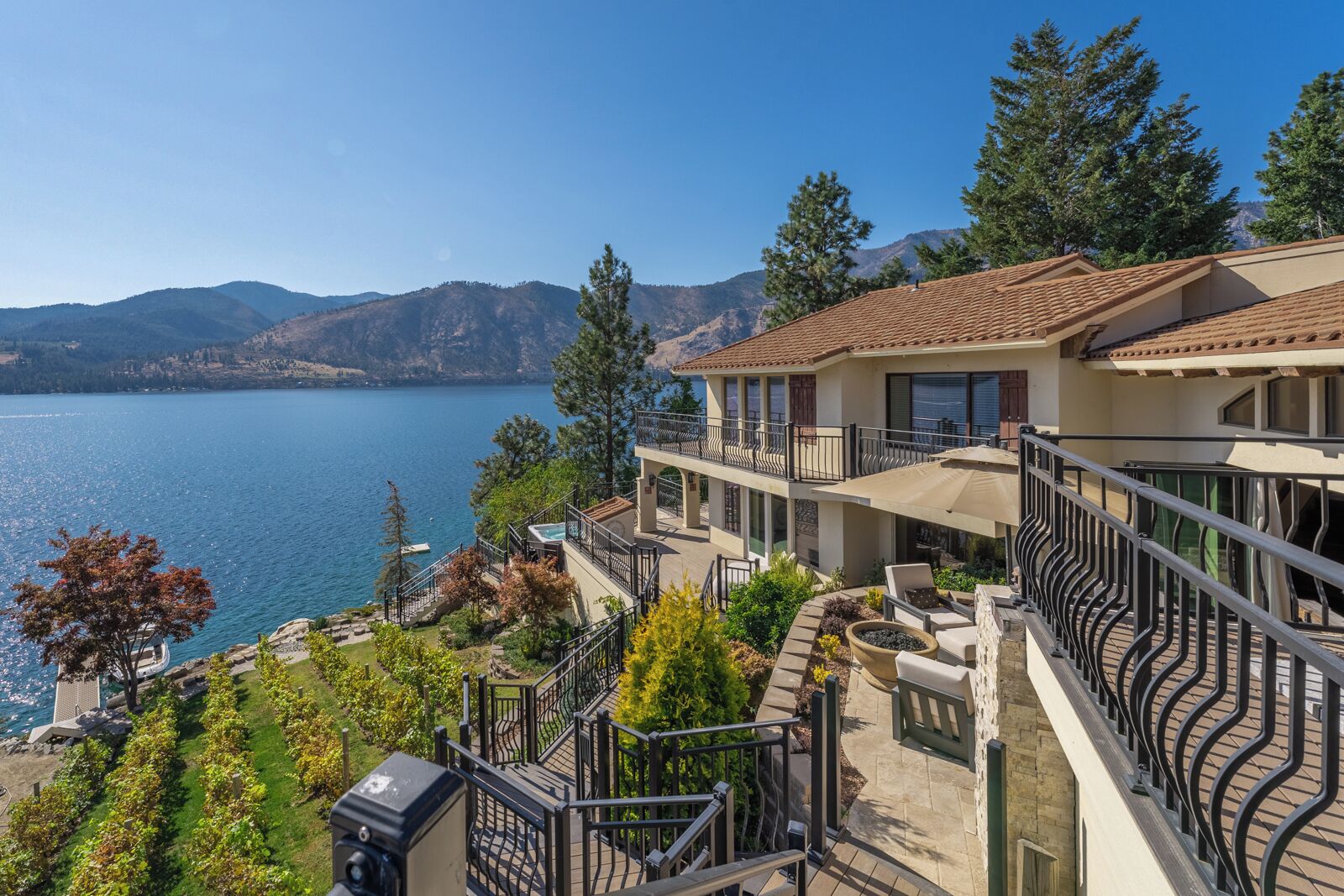 A two-story house with a balcony overlooking a lake and mountains.