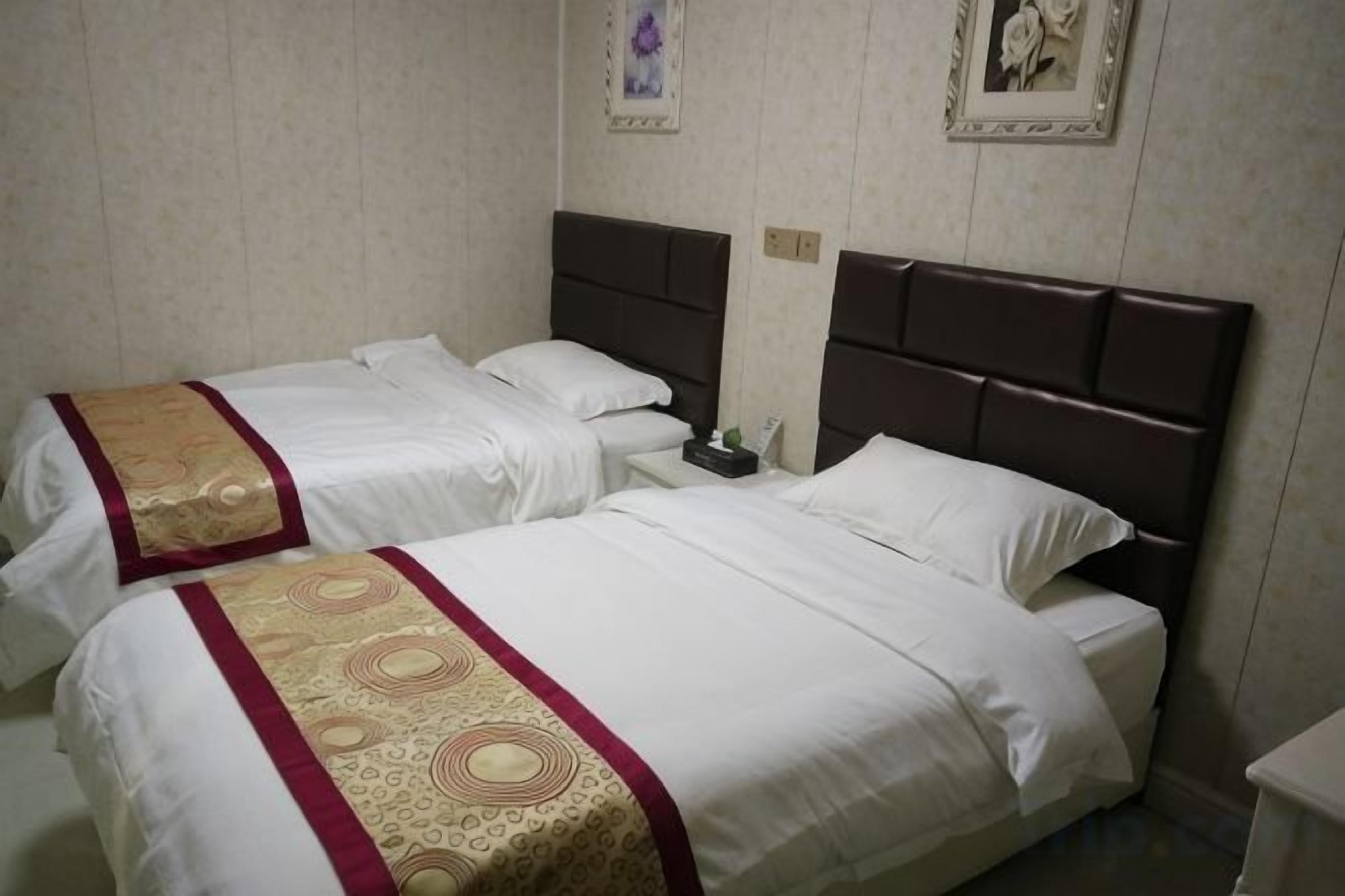 Une chambre d’hôtel avec deux lits, chacun doté d’une tête de lit et d’une couvre-lit décorative.