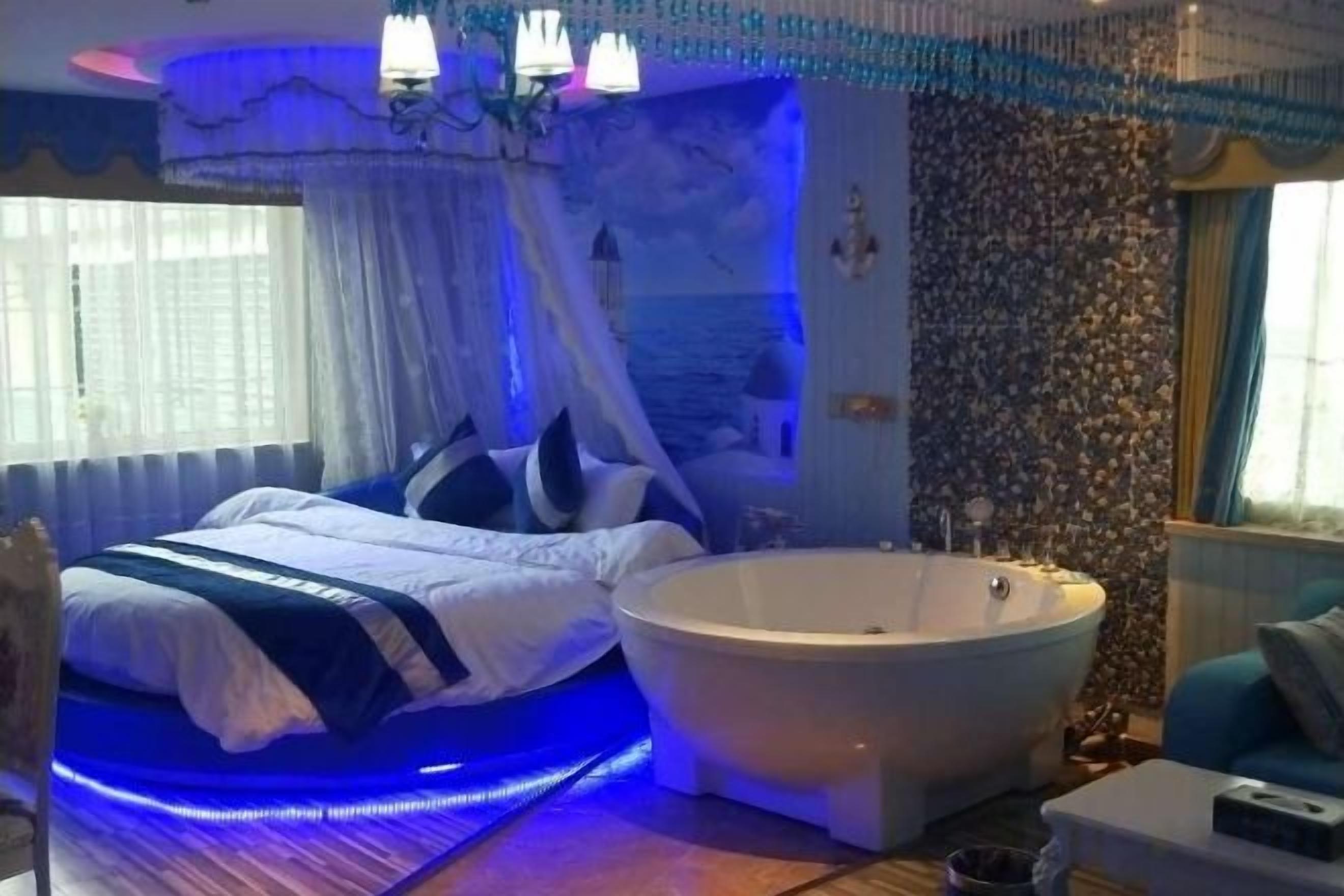 A bedroom with a bed, a bathtub, and a window.