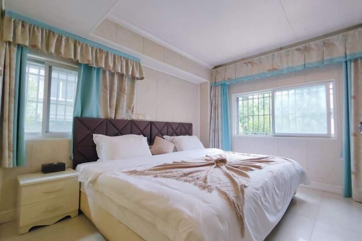 Un dormitorio con una cama grande, una mesita de noche y una ventana con cortinas.