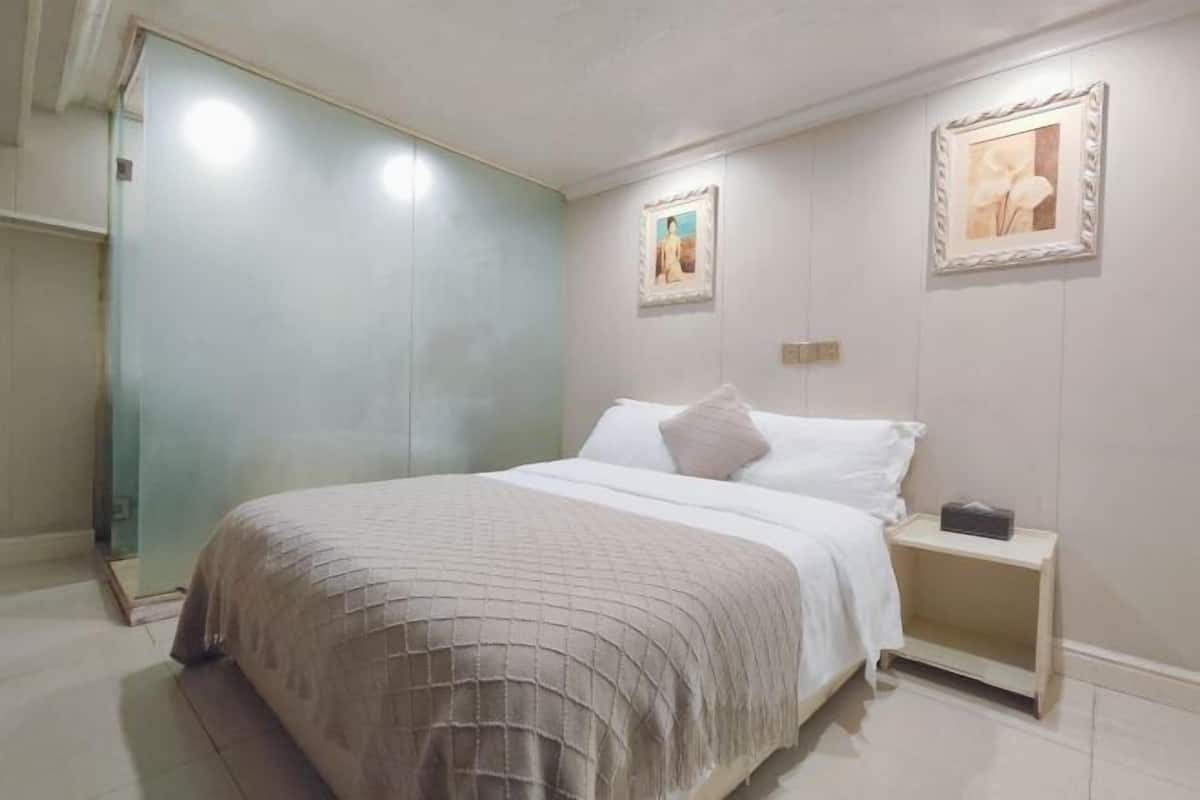 Un dormitorio con una cama, una mesita de noche y dos cuadros en la pared.