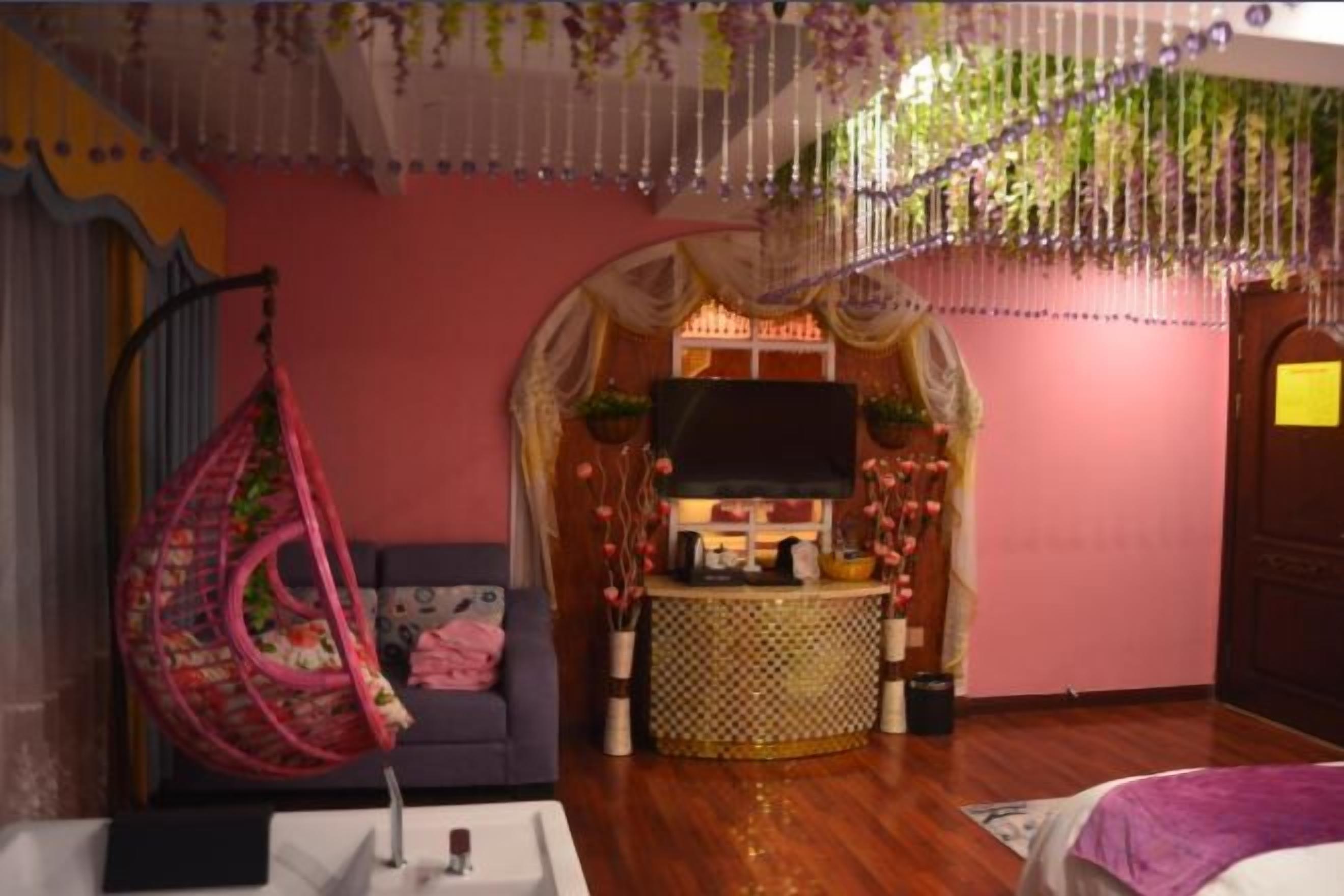 Una stanza con una poltrona a dondolo, una televisione, un tavolino e un arco decorativo.