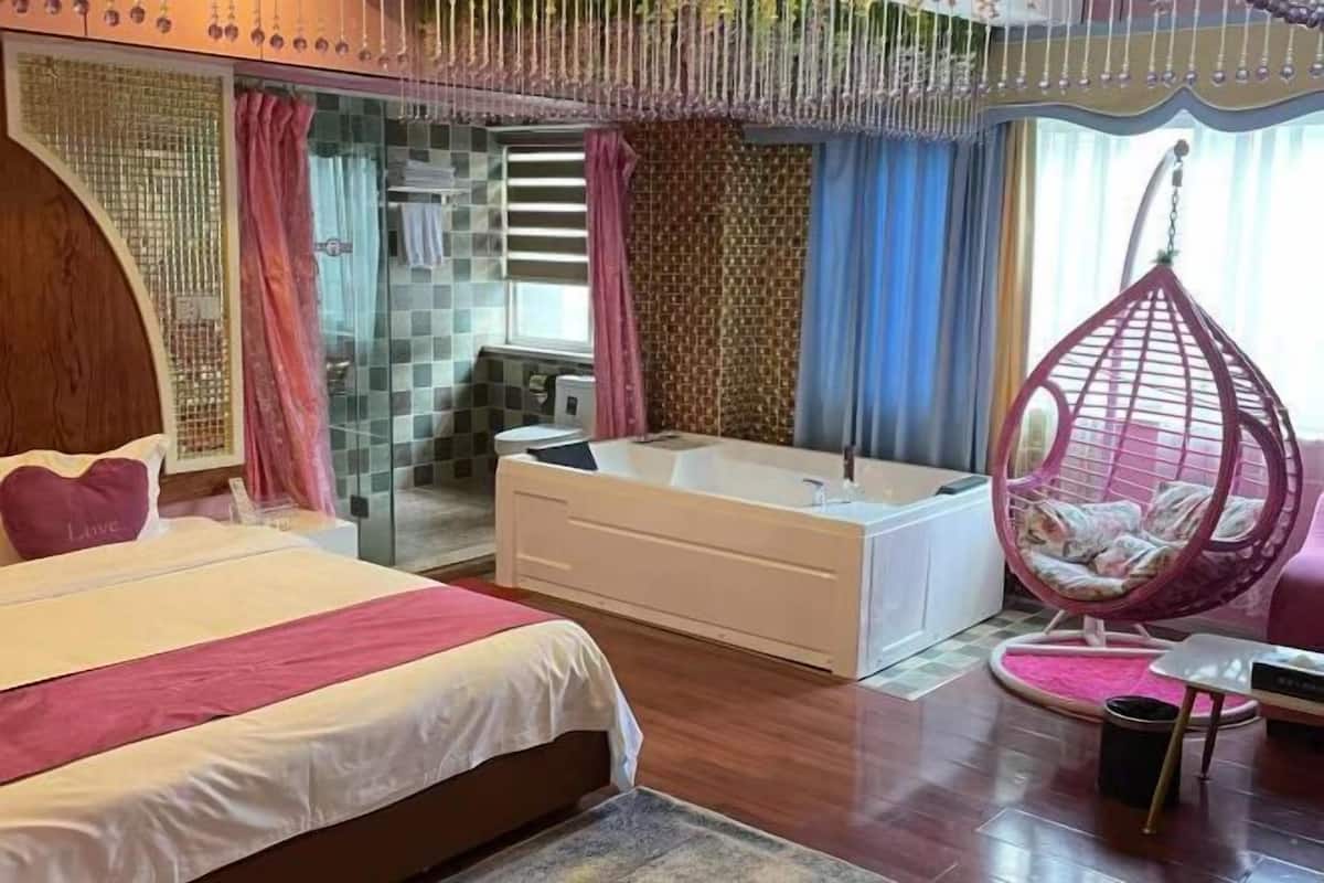 Un dormitorio con una cama, una bañera, un sillón colgante y una mesita.