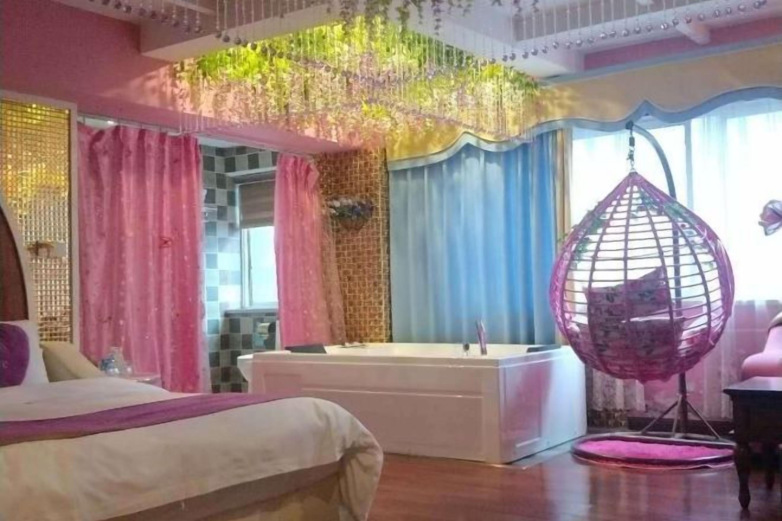 Una camera da letto con un letto, una poltrona sospesa e una vasca da bagno.