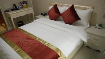 A hotel room with a bed, nightstand, and a desk with a lamp.