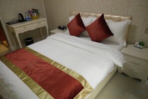 Una habitación de hotel con una cama, mesita de noche y escritorio con lámpara.