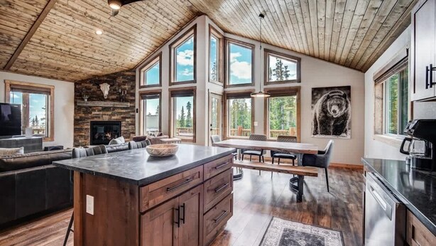 Una cocina amplia con una isla grande, techo de madera y ventanas grandes que ofrecen vistas al exterior.