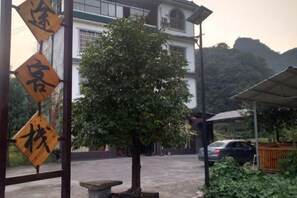 A building with a traditional architectural style, a tree in the foreground, and a parked car in the background. - Libo Maolan Mengtu Inn (Libo)