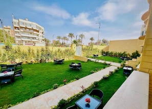 A courtyard with a well-maintained lawn, outdoor seating, and a view of surrounding buildings. - Turquoise Pyramids Gate (Giza)