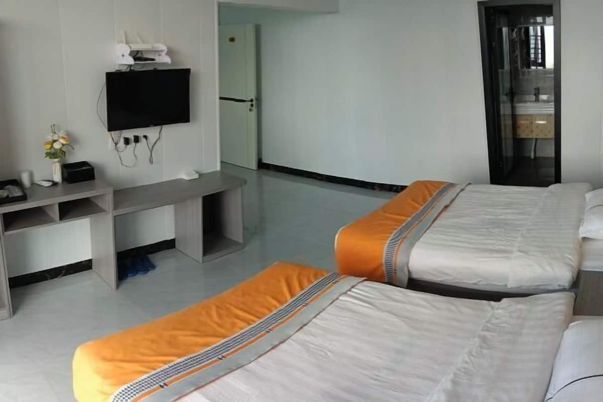 Hotellihuone, jossa on kaksi sänkyä, seinälle asennettu televisio, työpöytä ja kylpyhuone, joka on näkyvissä lasiovesta.