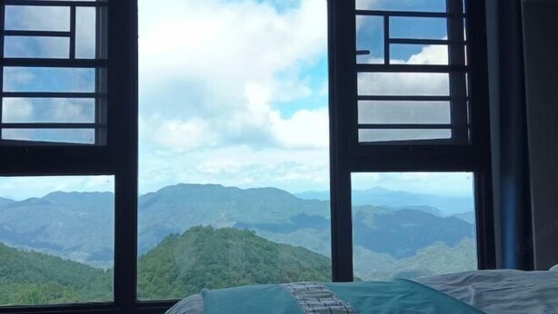 A room with a bed and a large window offering a view of a mountainous landscape.