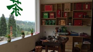 A room with a wooden table, chairs, a bookshelf, and a window with a view of trees and hills.