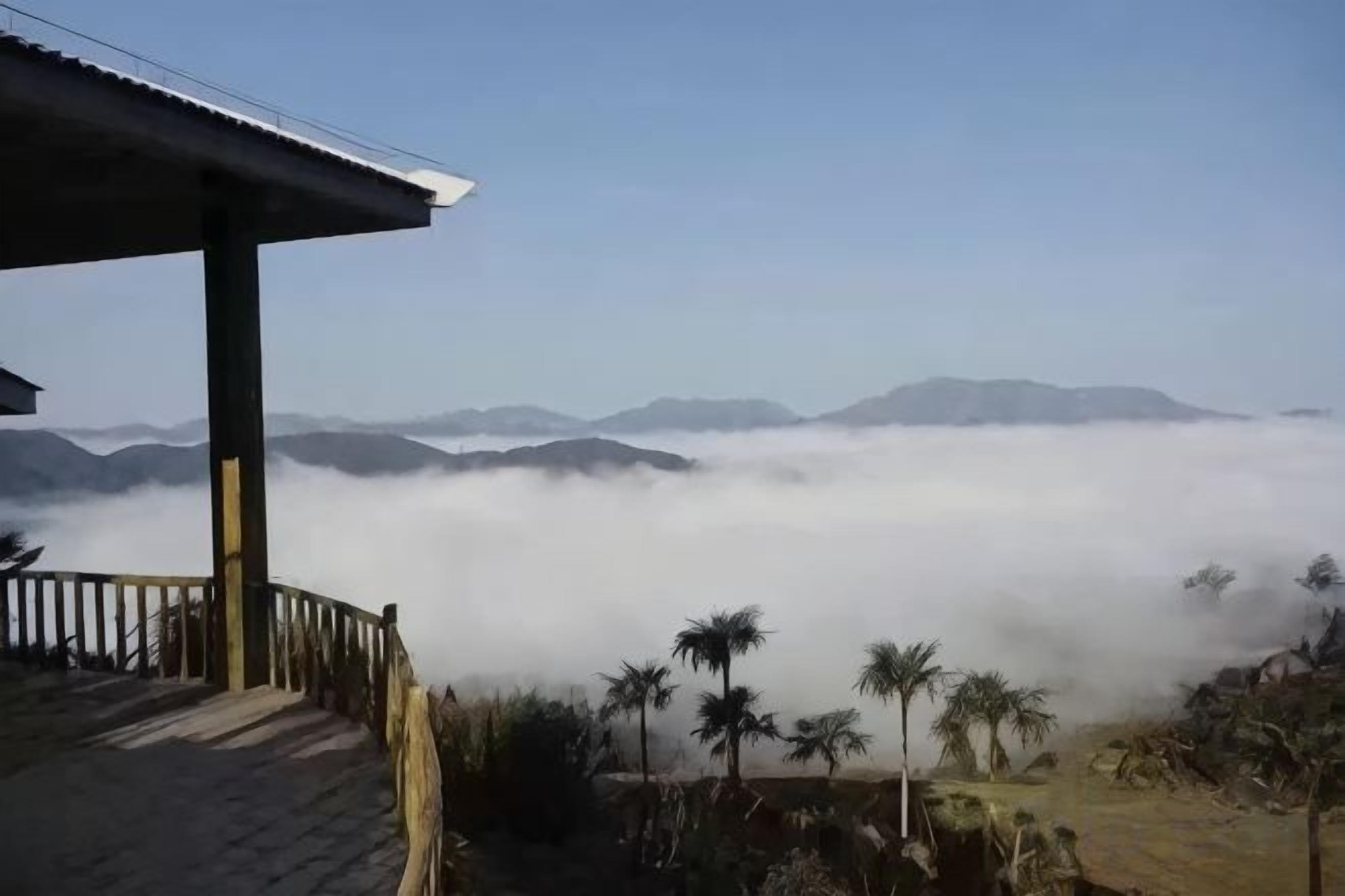 A wooden structure with a roof overlooking a mountainous landscape with a fog-covered valley.