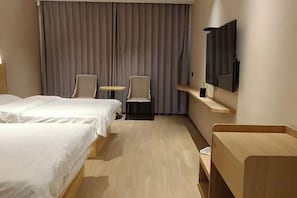 A hotel room with two beds, a small table, two chairs, a desk, and a mirror.