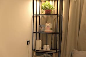 Una estantería con una planta en maceta, un dispensador de gel hidroalcohólico y un cuadro enmarcado.