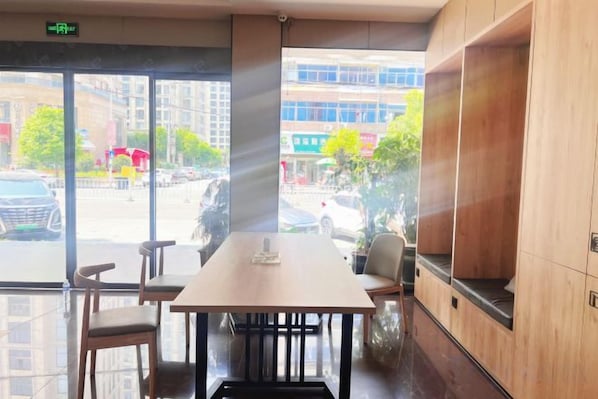 Habitación de hotel con un ventanal grande, una mesa de madera y una zona de estar.