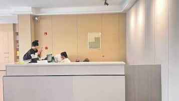 A reception desk with a counter, a security camera, and a bulletin board on the wall.