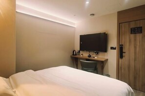 A hotel room with a bed, a desk with a chair, a television, and a wooden door. - Haocheng Business Hotel Ruian City (Rui'an)