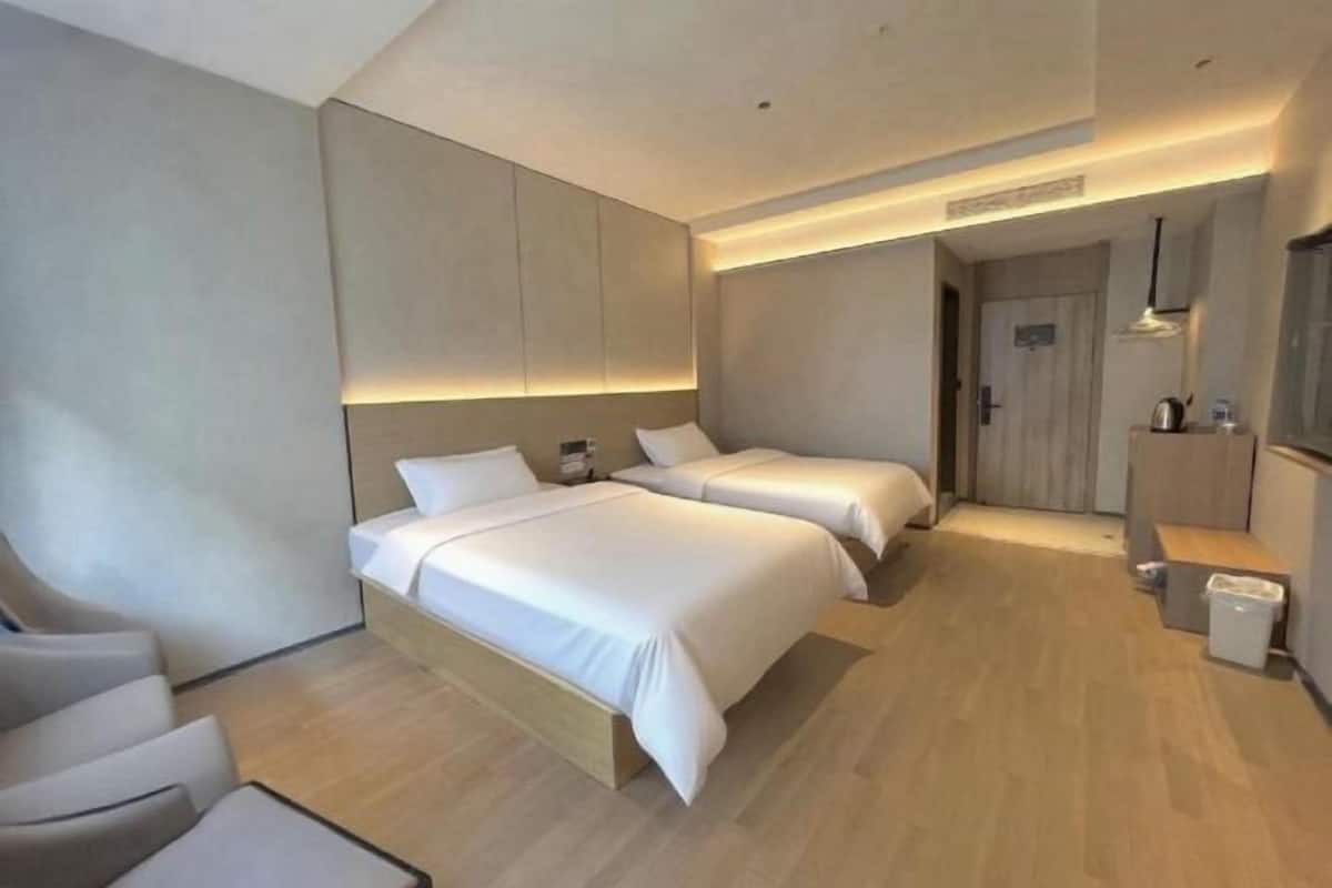 Ein modernes Hotelzimmer mit zwei Betten, einer Sitzecke und einer kleinen Küchenzeile.