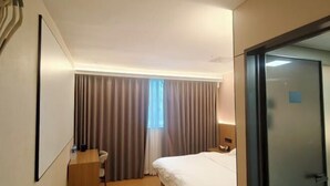 A hotel room with a bed, a desk, a chair, a window with curtains, and a door. - Haocheng Business Hotel Ruian City (Rui'an)