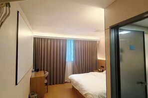 A hotel room with a bed, a desk, a chair, a window with curtains, and a door. - Haocheng Business Hotel Ruian City (Rui'an)
