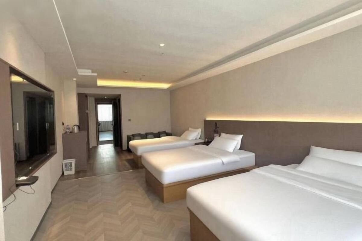 Ein Hotelzimmer mit zwei Betten, einem Fernseher, einem Schreibtisch und einem Spiegel.