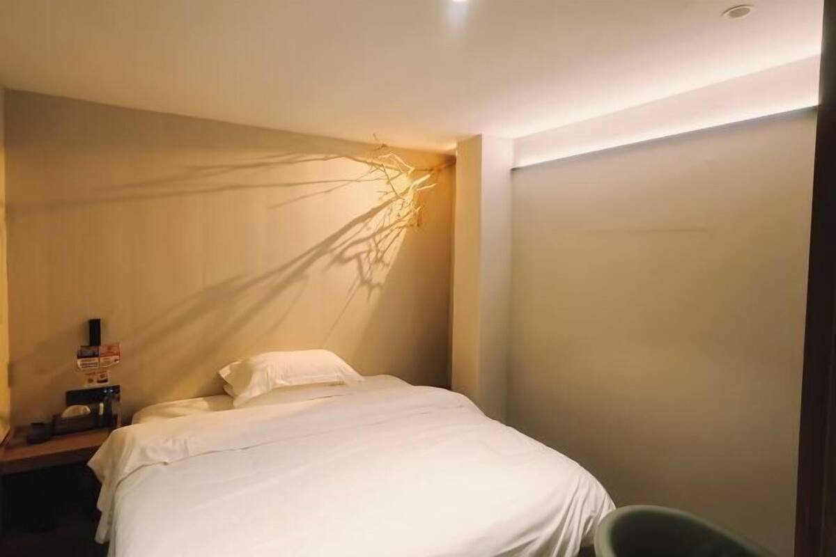 Ein Hotelzimmer mit Bett, Nachttisch, Wandleuchte und einer Tür.