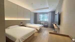 Ein modernes Hotelzimmer mit zwei Betten, einem Schreibtisch, einem Stuhl, einem Fernseher und einem Fenster.