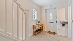 A hallway with a wooden console table, a door, and a window with blinds.