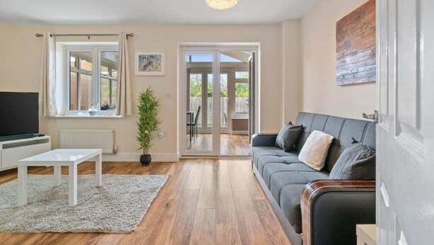 A modern living room with a sofa, a TV, a coffee table, and a large window.
