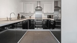 A modern kitchen with black and white cabinetry, stainless steel appliances, and a central island.