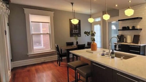 Une cuisine moderne dotée d’un grand îlot central, de luminaires suspendus et offrant une vue sur l’extérieur.