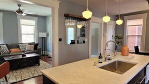 Une cuisine moderne dotée d’un îlot central, de luminaires suspendus et d’un coin repas avec une table et des chaises.