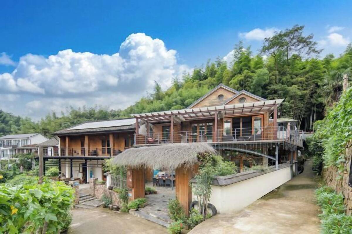 Una casa de madera tradicional con techo de paja, un balcón y un jardín.