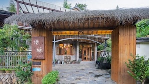 A traditional wooden building with a thatched roof entrance, stone pathway, and a signboard. - Moganshan Xiyuan Inn (Deqing)